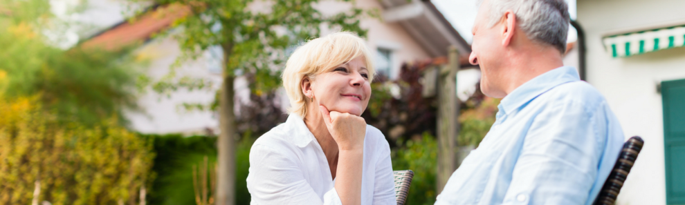 Seniorenpaar sitzt im Garten ihres Hauses